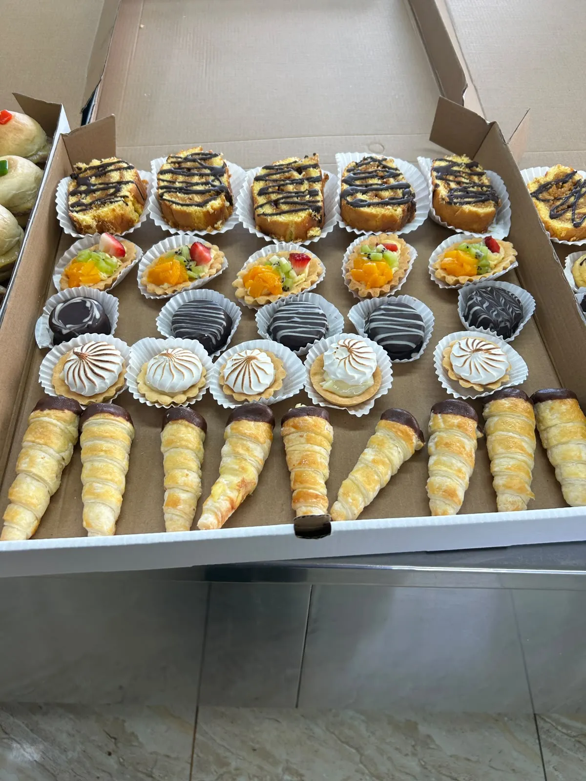 Bandeja de pastelería: queques, tartaletas de fruta, chocolates, merengues y cachitos