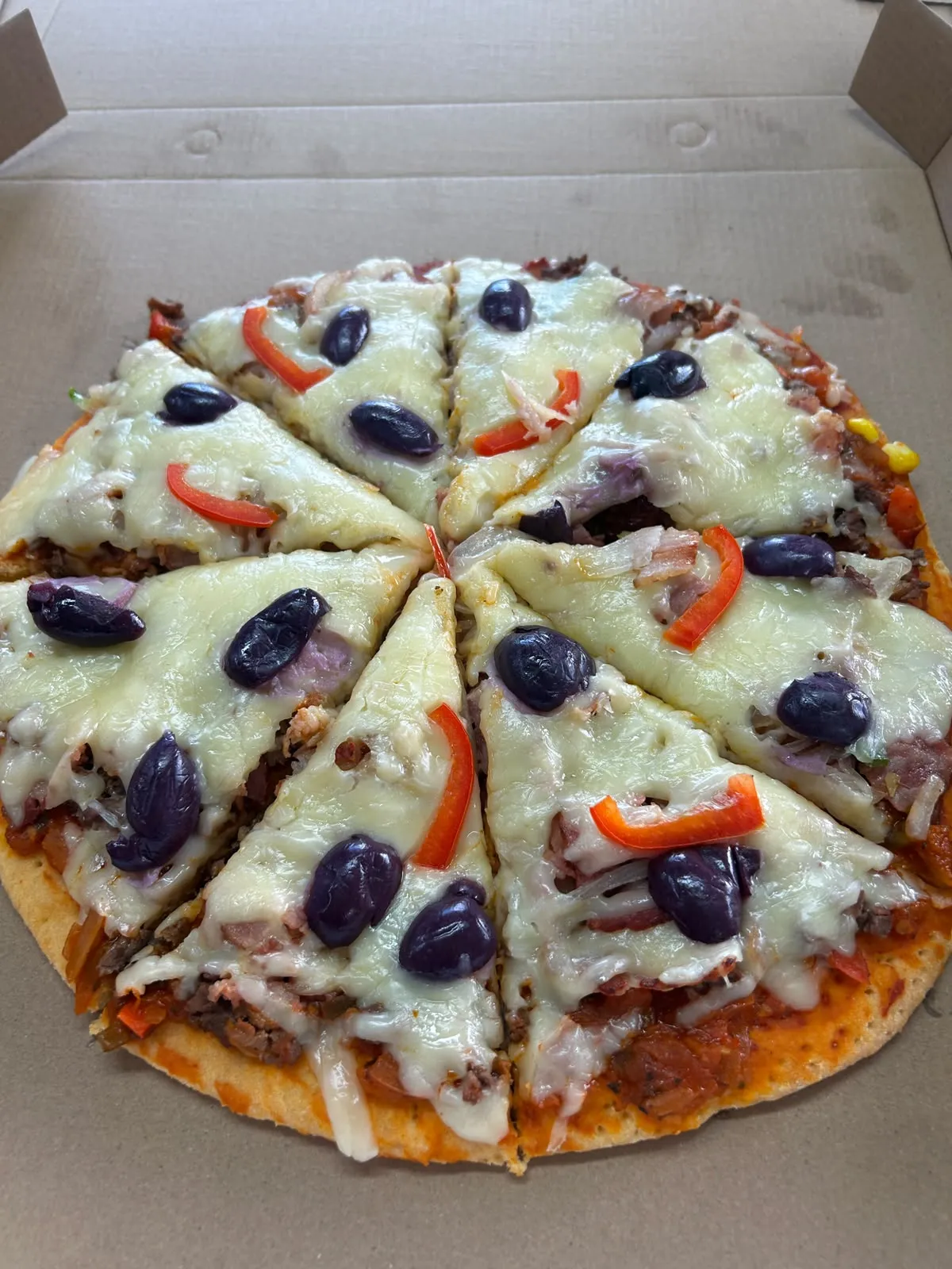 Pizza con carne, tocino, pimentón rojo, aceitunas y queso
